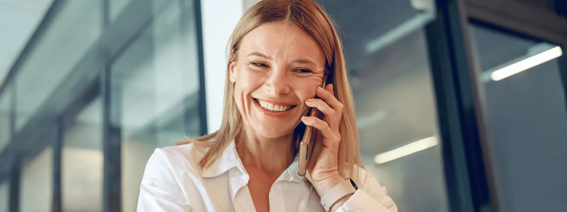 Mulher branca sorrindo ao telefone