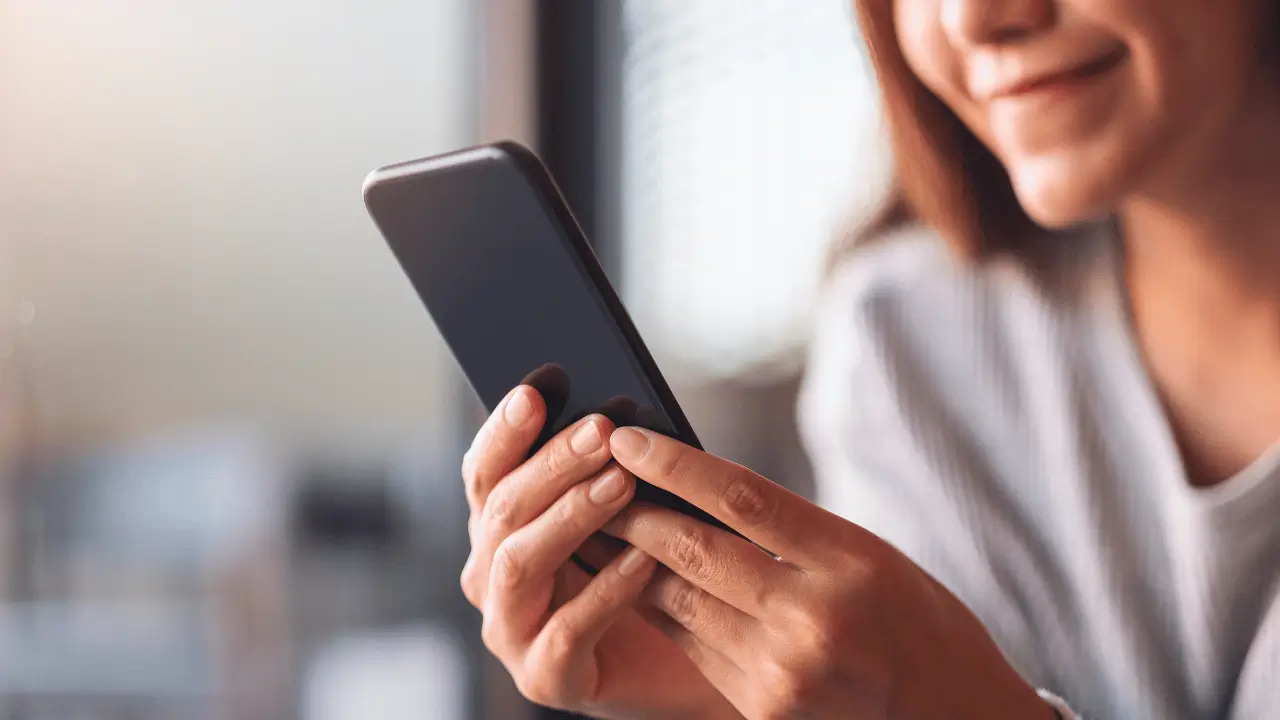 Mulher desfocada com o celular na mão