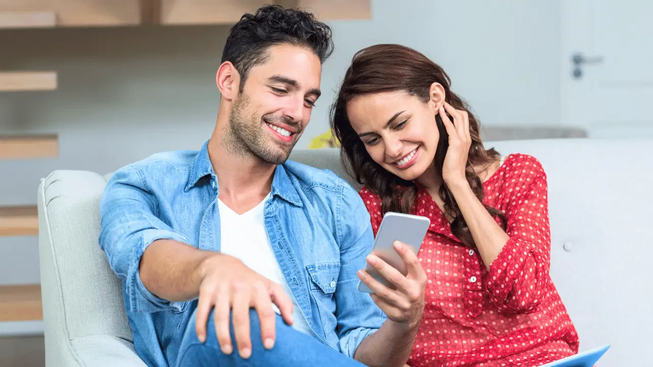 Casal sorrindo vendo um telefone celular