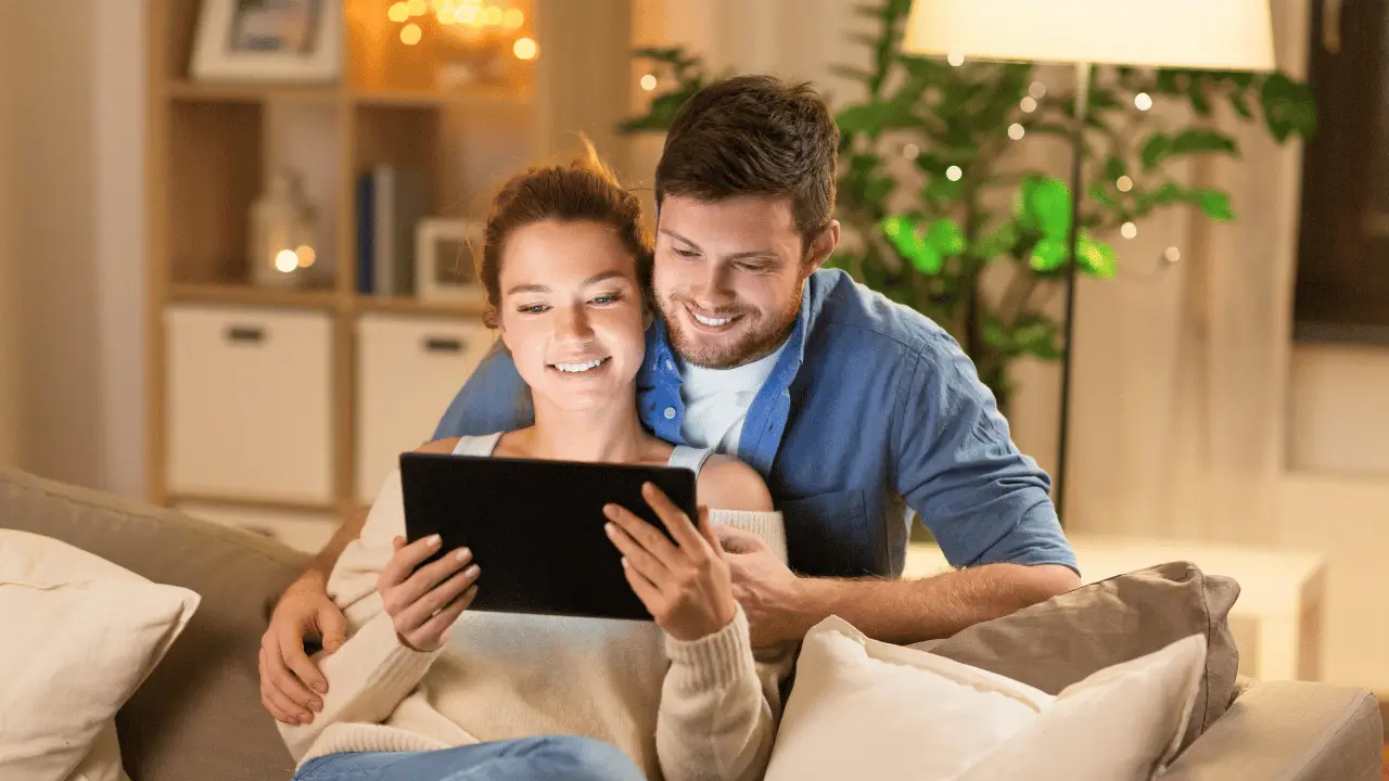 Casal sorrindo vendo um tablet