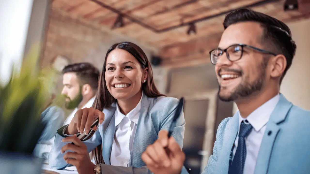 Homem e mulher sorrindo em frente a um computador
