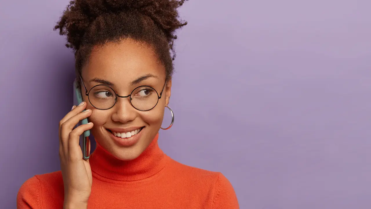 Mulher negra sorrindo falando ao celular