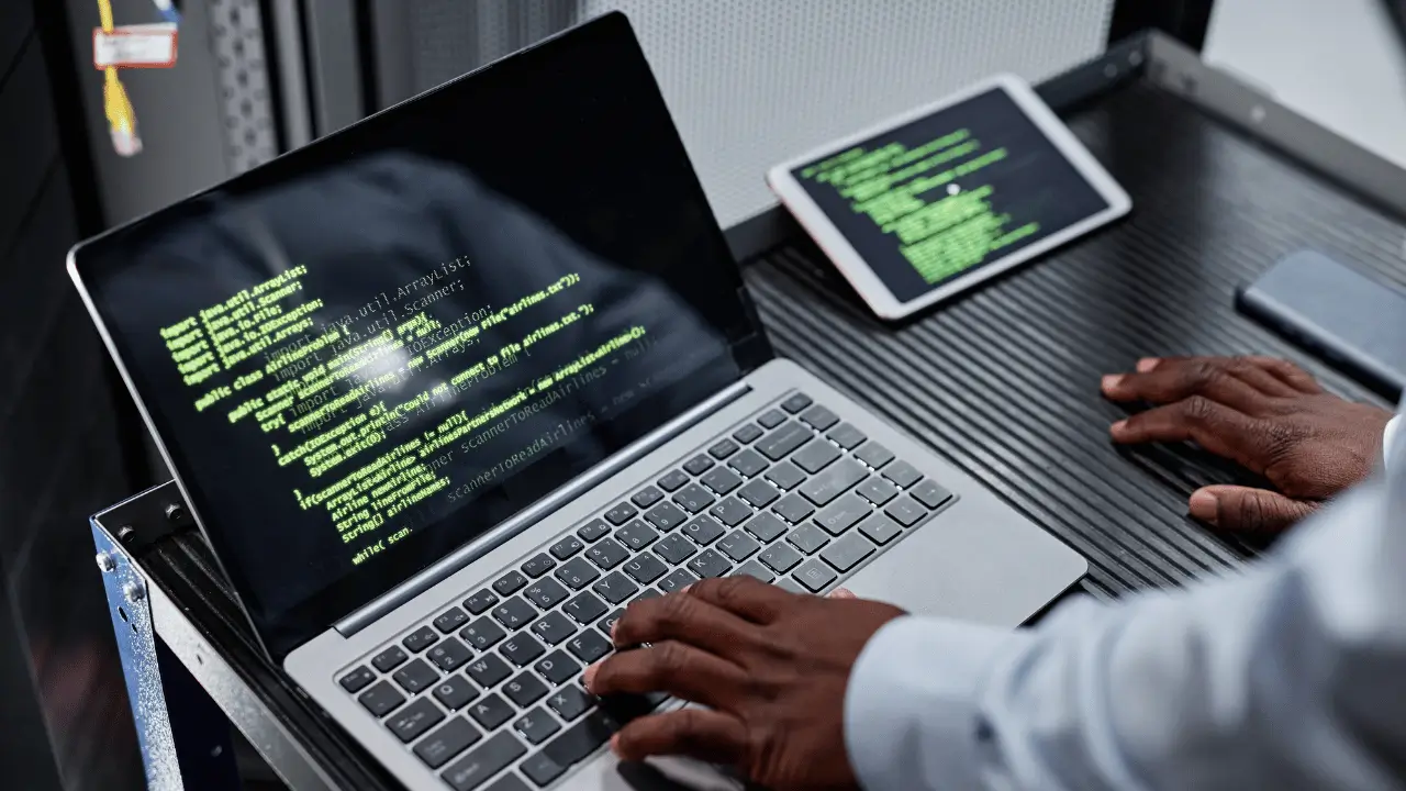 Mão negra teclando em um notebook cinza