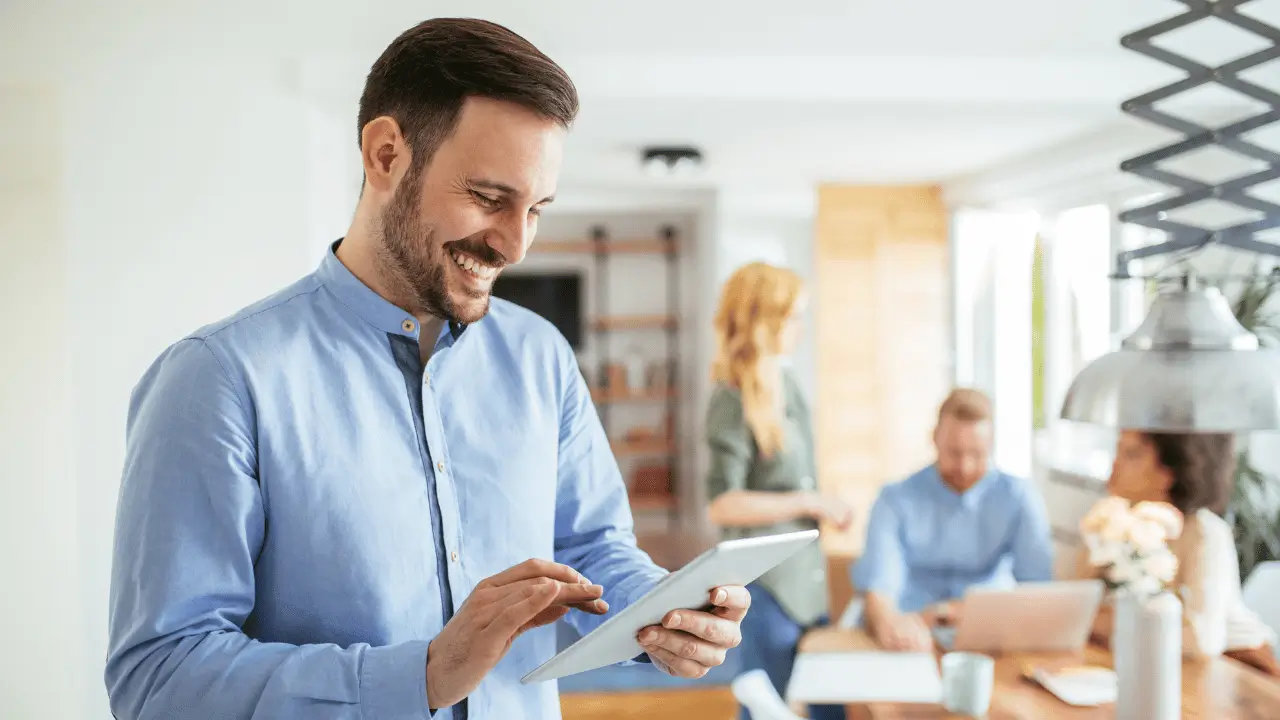 Homem sorrindo com um tablet nas mãos 