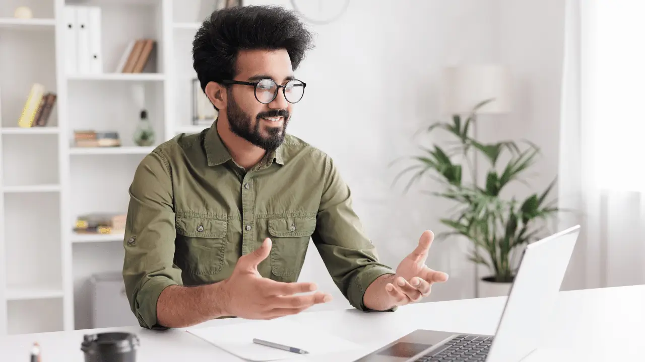 Homem gesticulando em frente a um notebook branco