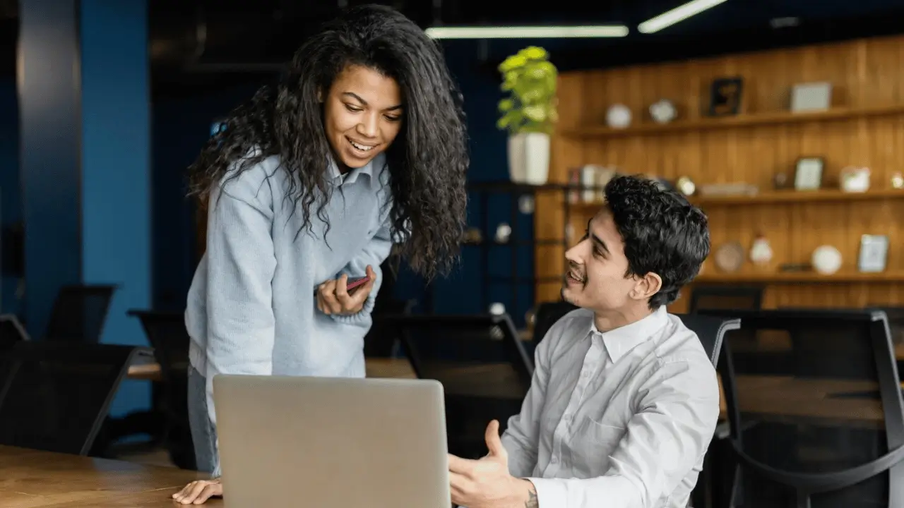 Homem e mulher conversando em frente a um computador
